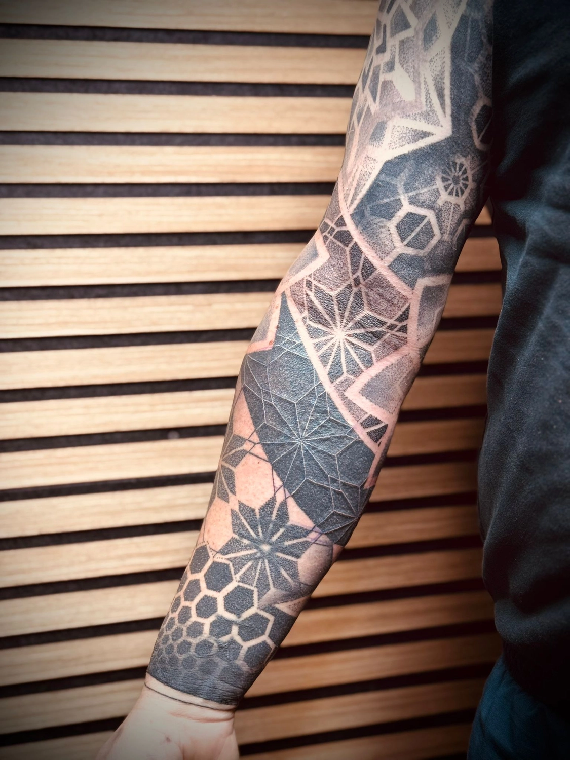 Kunstraum – Tätowierung – Schwarz-graue geometrische Formen als Tätowierung auf dem gesamten Arm