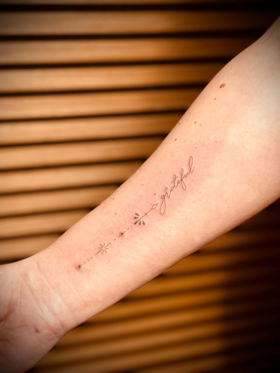 Kunstraum – Tätowierung – Schwarz-graue Schrift-Tätowierung auf dem Arm