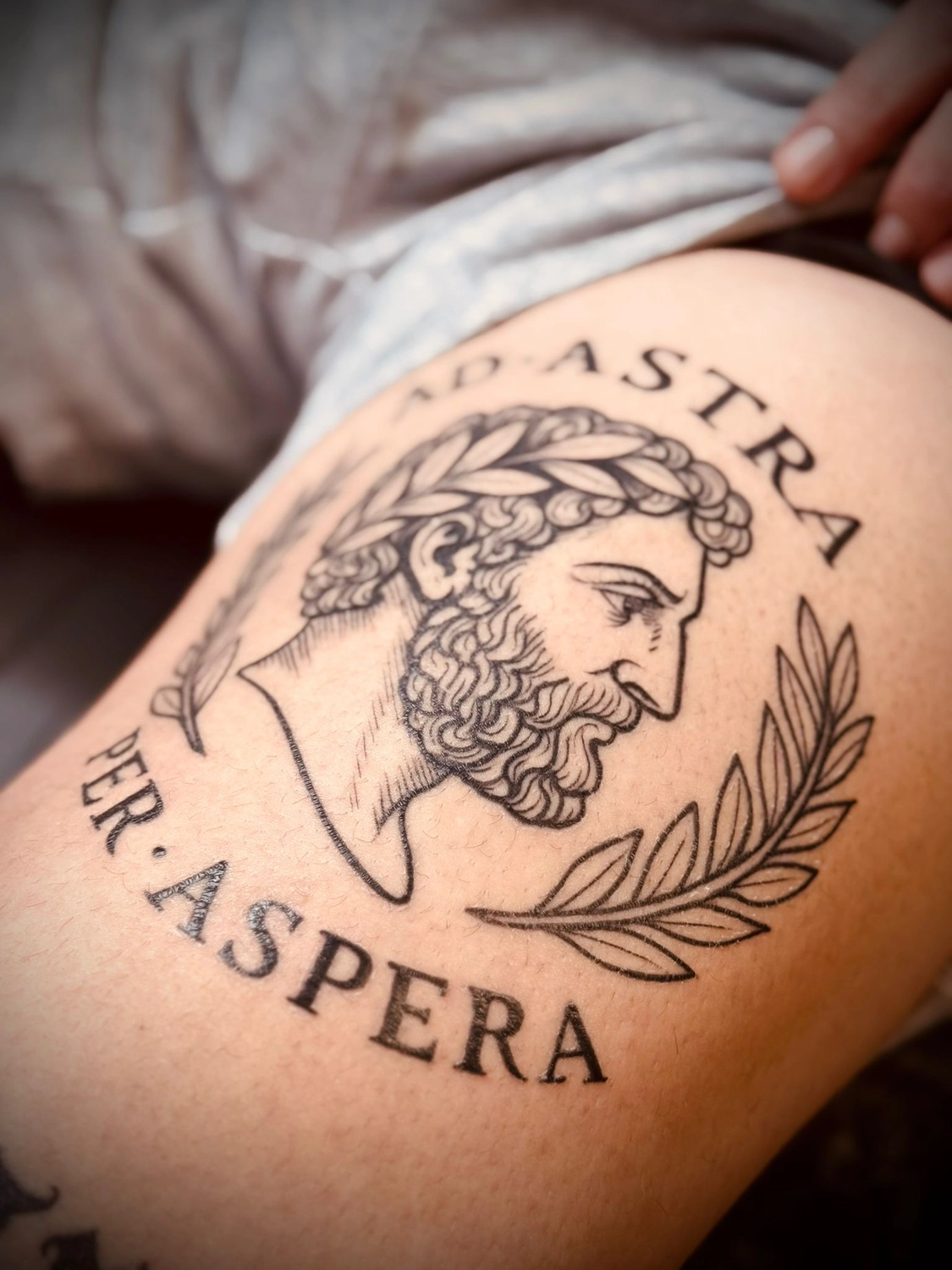 Kunstraum – Tätowierung – Schwarz-Grau-Tätowierung eines bärtigen Mannes mit dem Schriftzug PER ASPERA