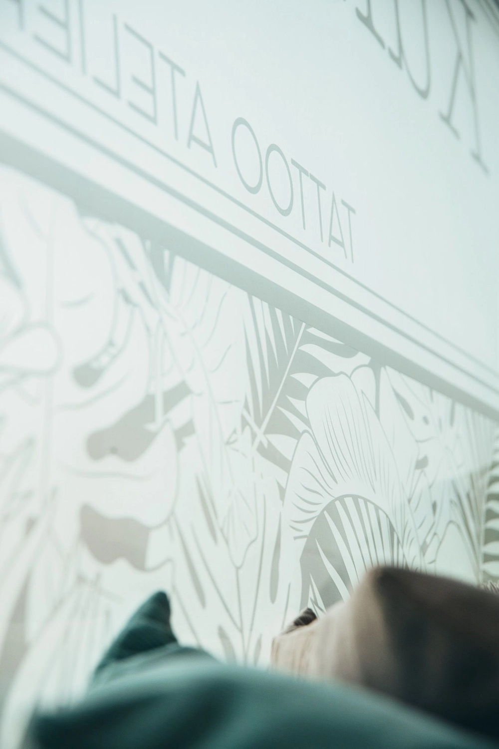 Kunstraum – Tätowierungsarbeit – Weiße Wand mit grauer Blumendekoration darauf