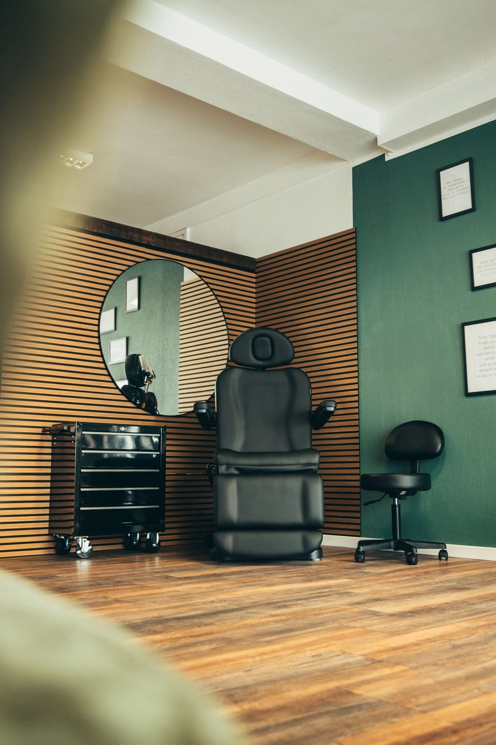 Kunstraum – Tätowierungsarbeiten – Schwarze Ledersessel und Beistelltisch vor einer Holzwand