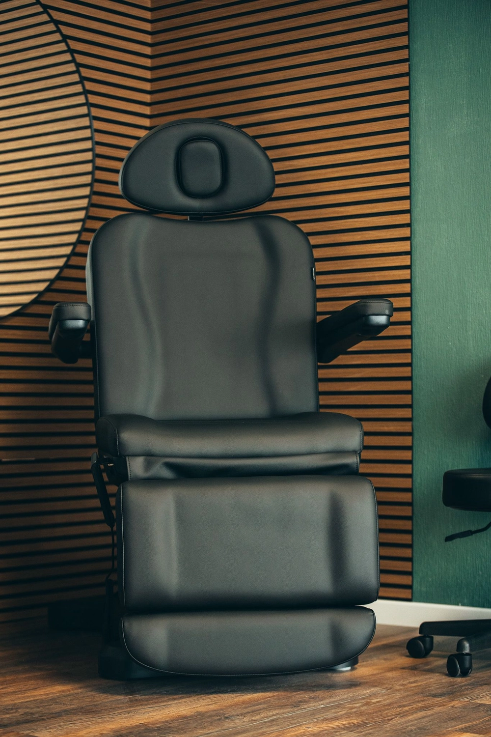 Kunstraum – Tätowierungsarbeit – Schwarzer Ledersessel vor einer Holzwand