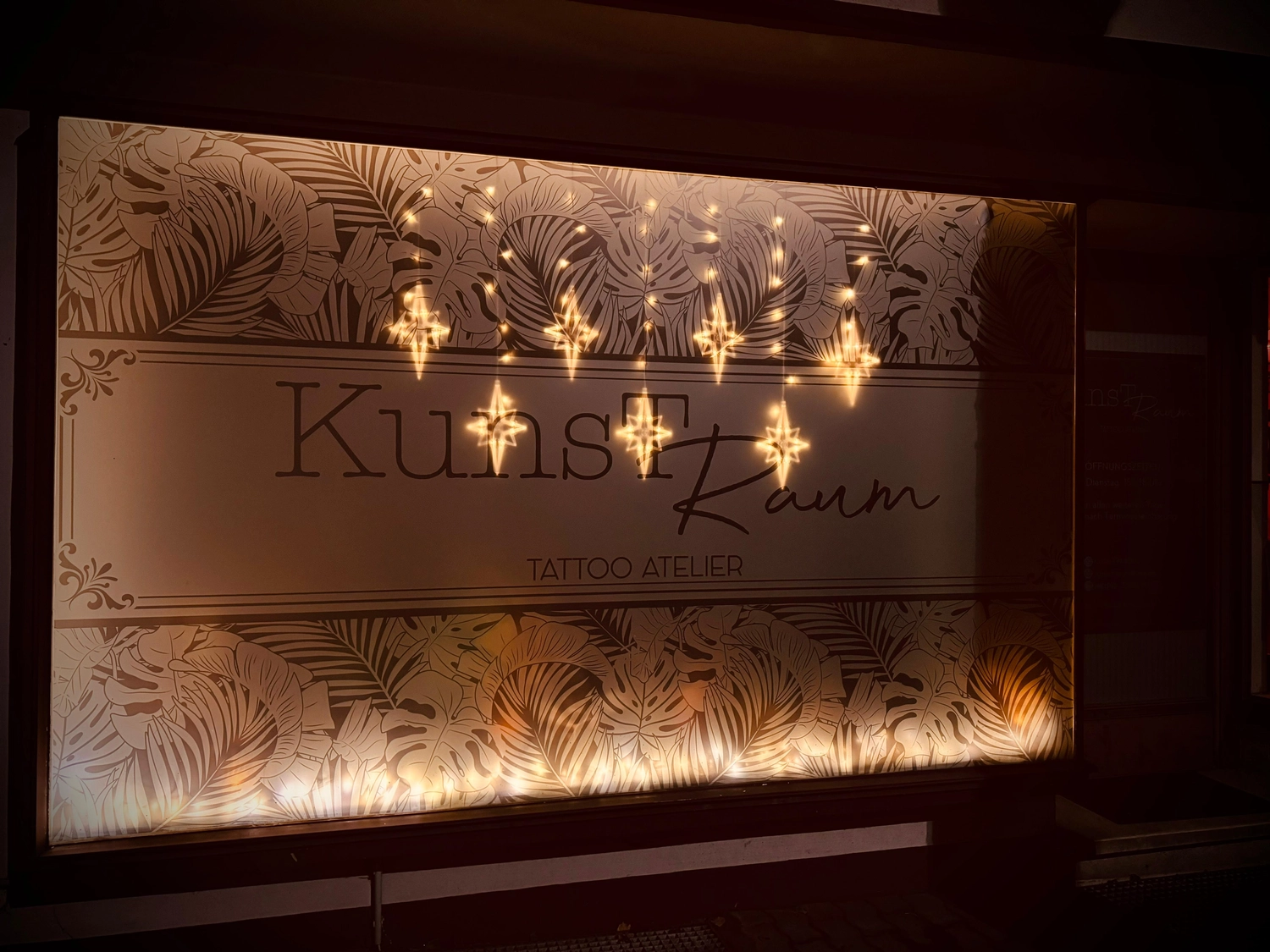 Kunstraum – Tattoo-Arbeit – Kunstraum-Tafel mit Dekoration und sternförmigen Lichtern.